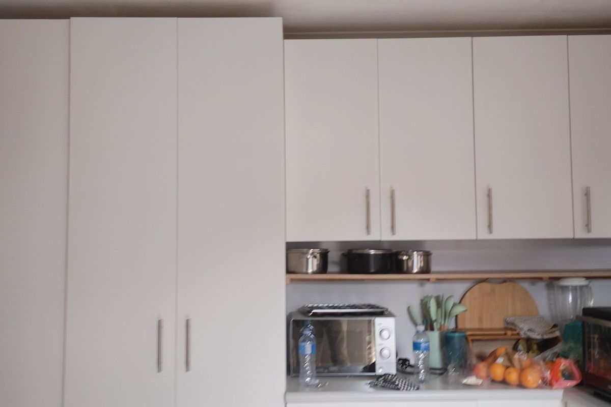 A kitchen area featuring white built-in cabinetry, laminate countertops, and open shelving for storage.