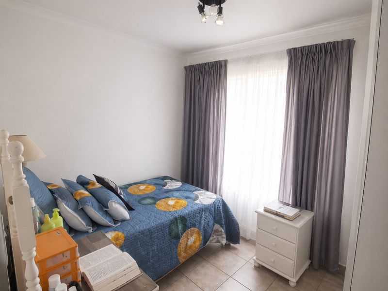 A functional bedroom featuring tiled flooring, a ceiling light fixture, and a built-in wardrobe, offering a clean and simple living space.