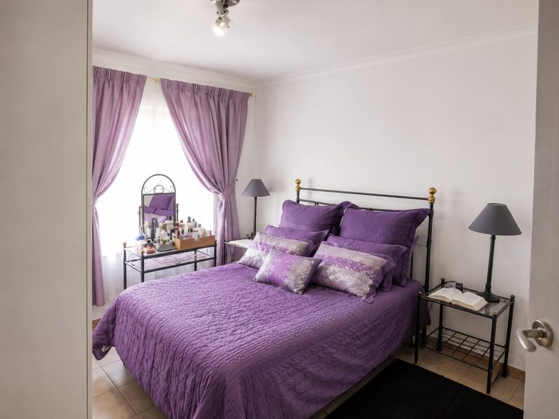 A well-maintained bedroom featuring tiled flooring, neutral walls, and a ceiling-mounted light fixture, offering a clean and functional living space.