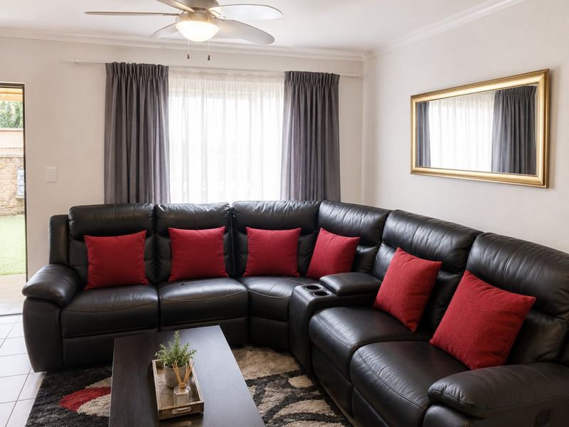 A well-maintained living room featuring a ceiling fan and tiled flooring, with direct access to an outdoor area.