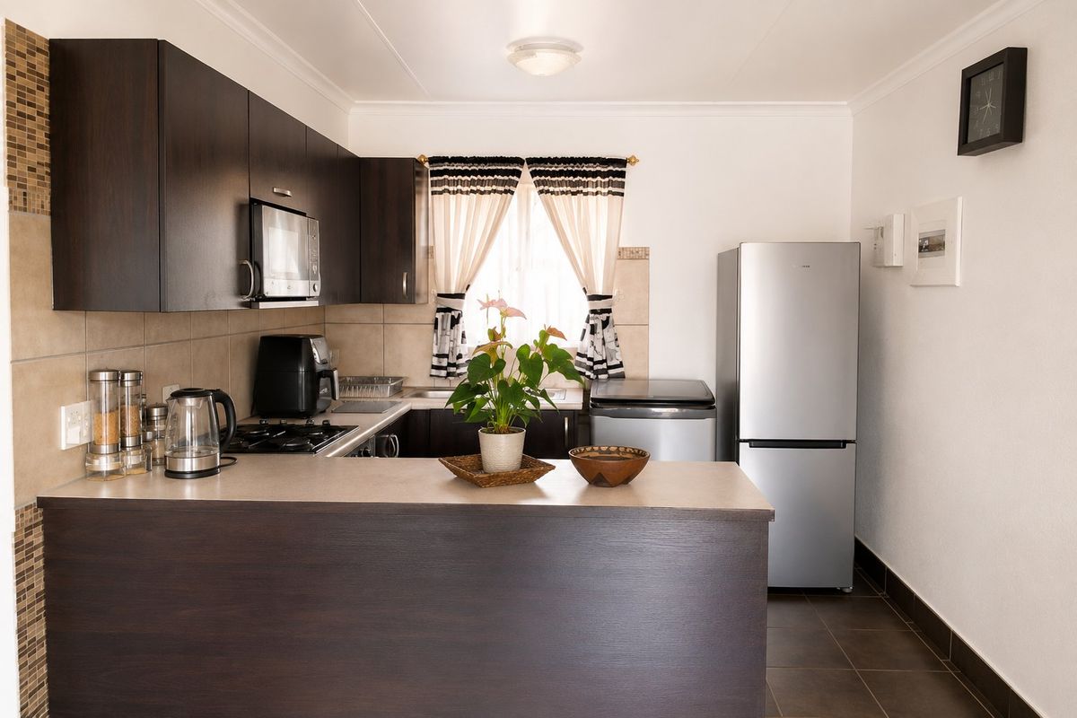 A functional kitchen featuring dark wood cabinetry, a breakfast bar, tiled backsplash, and built-in appliances, offering a practical layout for daily use.