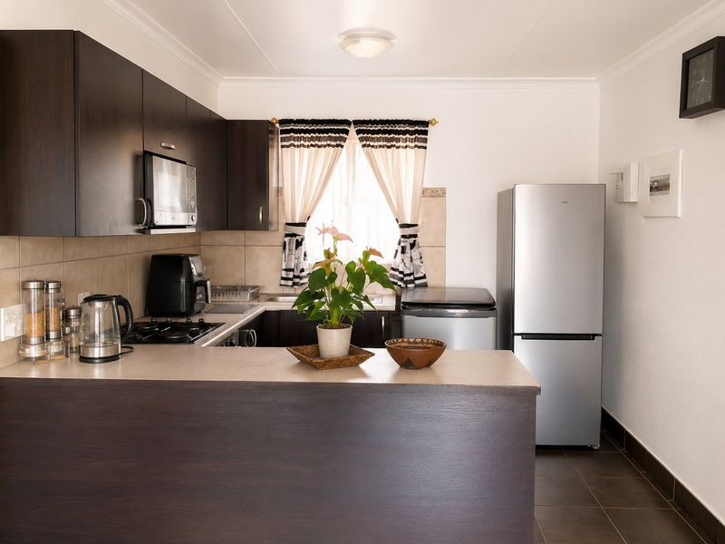 A functional kitchen featuring dark wood cabinetry, a breakfast bar, tiled backsplash, and built-in appliances, offering a practical layout for daily use.