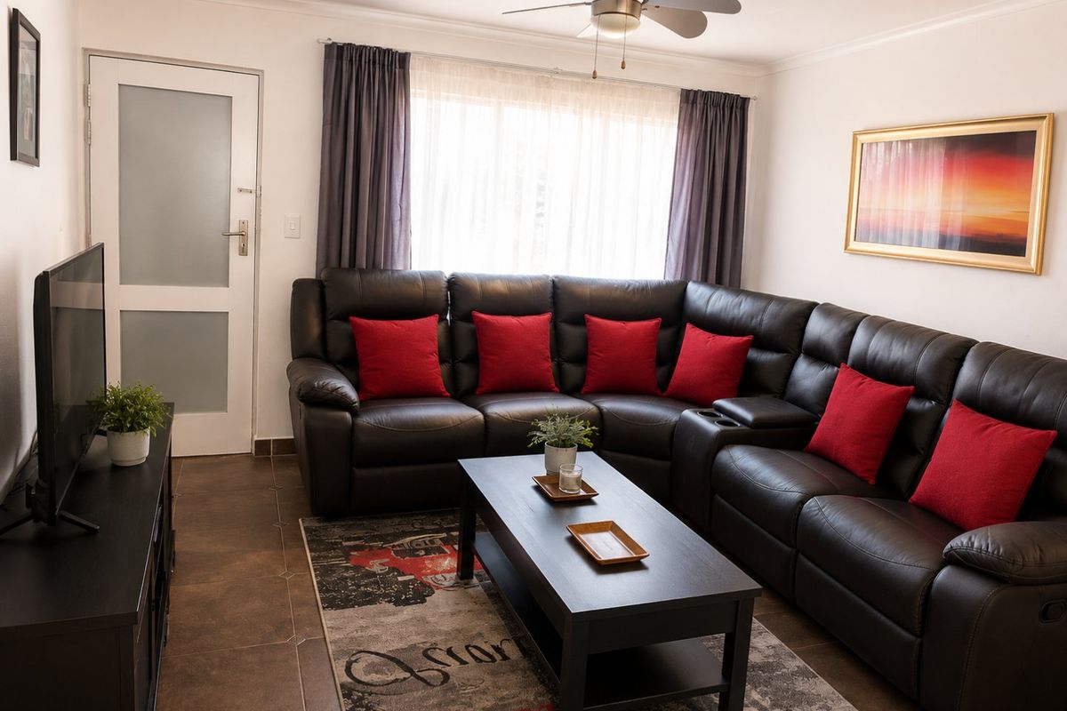 A well-maintained living room featuring tiled flooring, a ceiling fan, and a frosted glass panel door, providing a comfortable and functional living space.