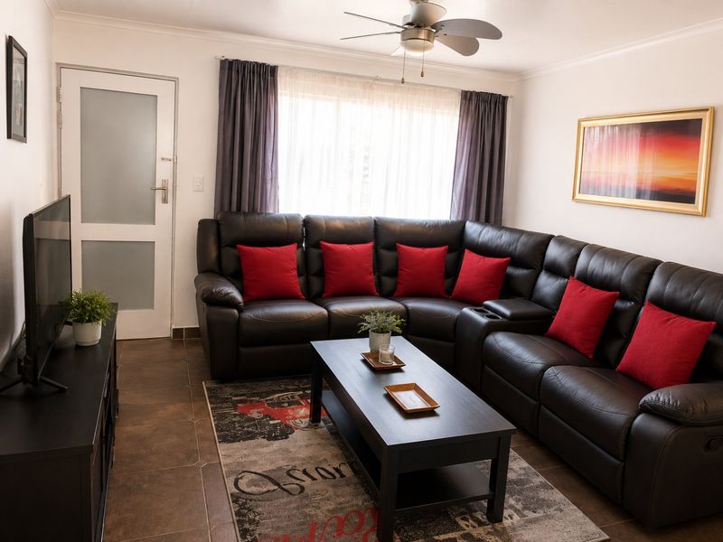 A well-maintained living room featuring tiled flooring, a ceiling fan, and a frosted glass panel door, providing a comfortable and functional living space.