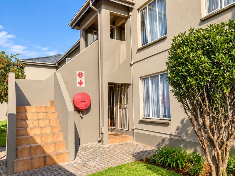 Exterior view of an apartment building entrance featuring a paved walkway, tiled staircase, and installed fire safety equipment.
