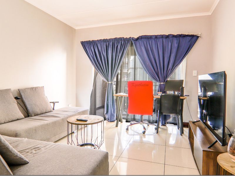 A bright living room featuring large format floor tiles and a sliding glass door providing access to the exterior.