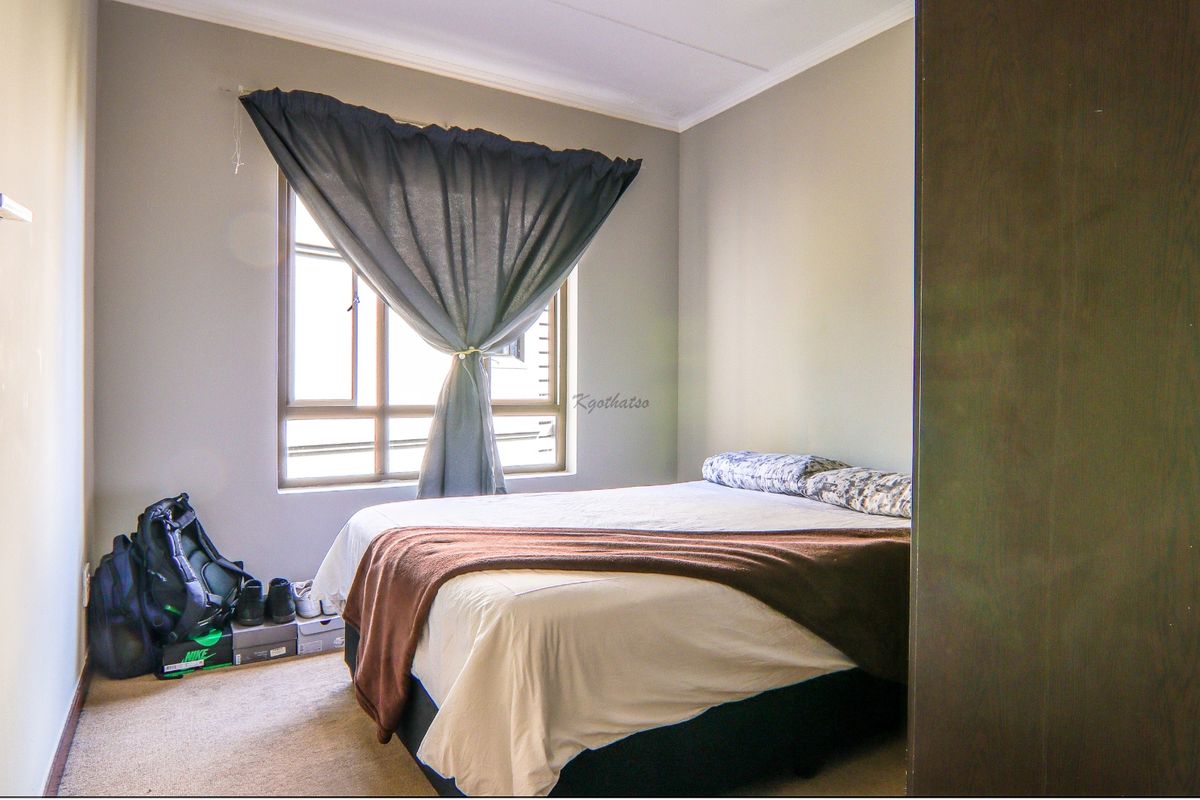 A functional bedroom featuring neutral wall tones, carpeted flooring, and a built-in wardrobe, providing a comfortable and practical living space.