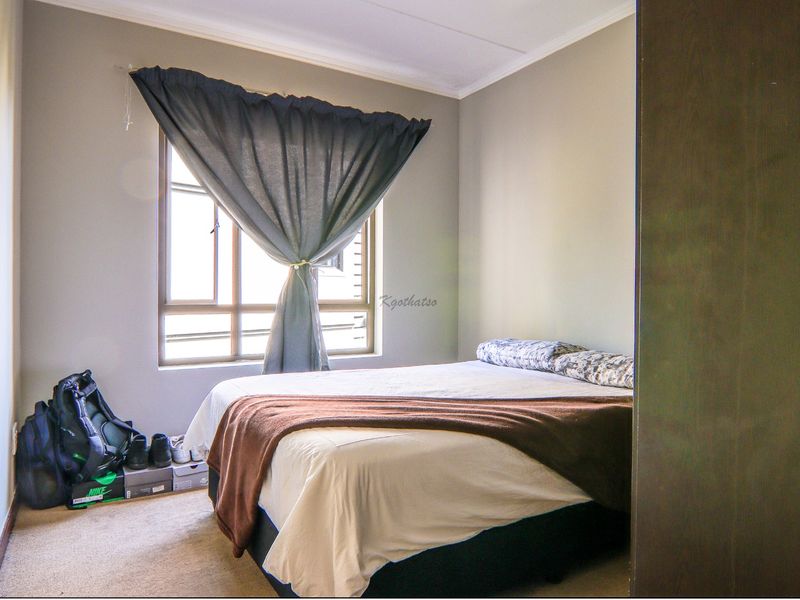 A functional bedroom featuring neutral wall tones, carpeted flooring, and a built-in wardrobe, providing a comfortable and practical living space.