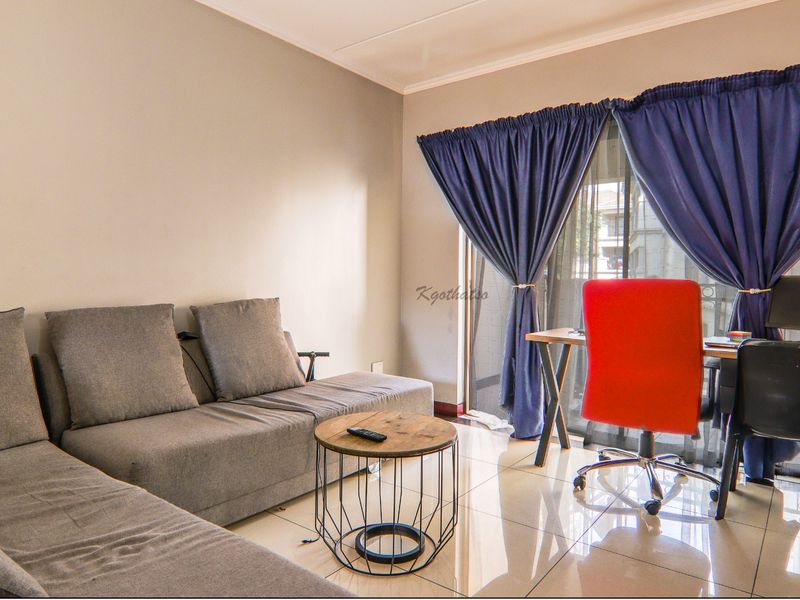 A living room area featuring tiled flooring and a sliding glass door providing access to the exterior.