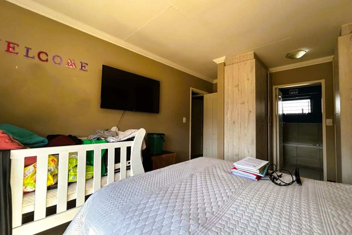 A bedroom featuring built-in cupboards and coving, with an adjoining bathroom visible through the doorway.