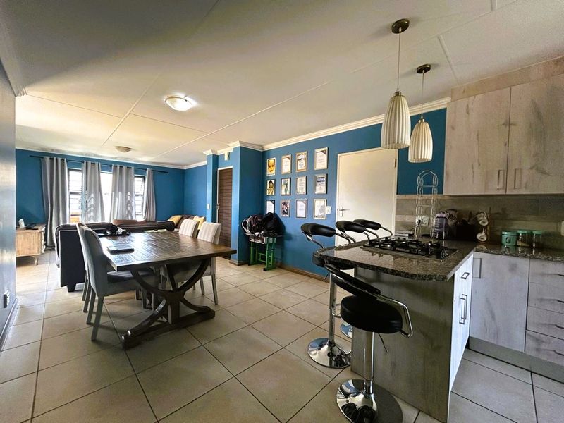 Open-plan living and dining area featuring a kitchen with granite countertops, gas hob, tiled flooring, and modern pendant lighting.