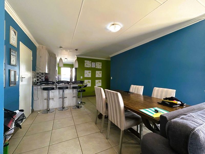 Open-plan dining and kitchen area featuring tiled flooring, a breakfast bar, and a dedicated dining space with vibrant wall accents.