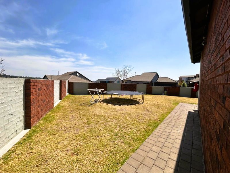 A private rear garden featuring a paved walkway, lawn area, and secure brick boundary walls.