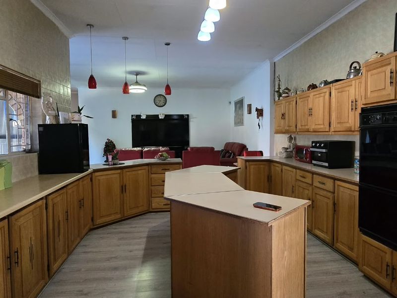 Spacious open-plan kitchen featuring extensive wooden cabinetry, laminate countertops, and integrated oven, flowing into the adjacent living area.