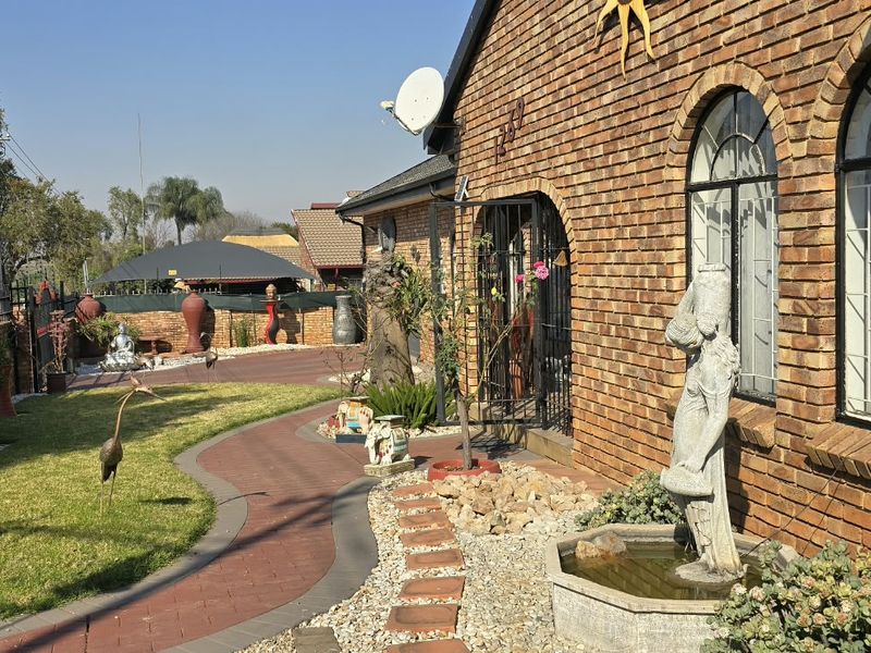 Front exterior view of a face brick house featuring arched windows, a paved garden walkway, and secure boundary walling.