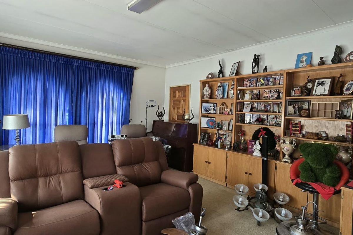 A living room featuring a large built-in wooden shelving unit, carpeted flooring, and coved ceiling details.