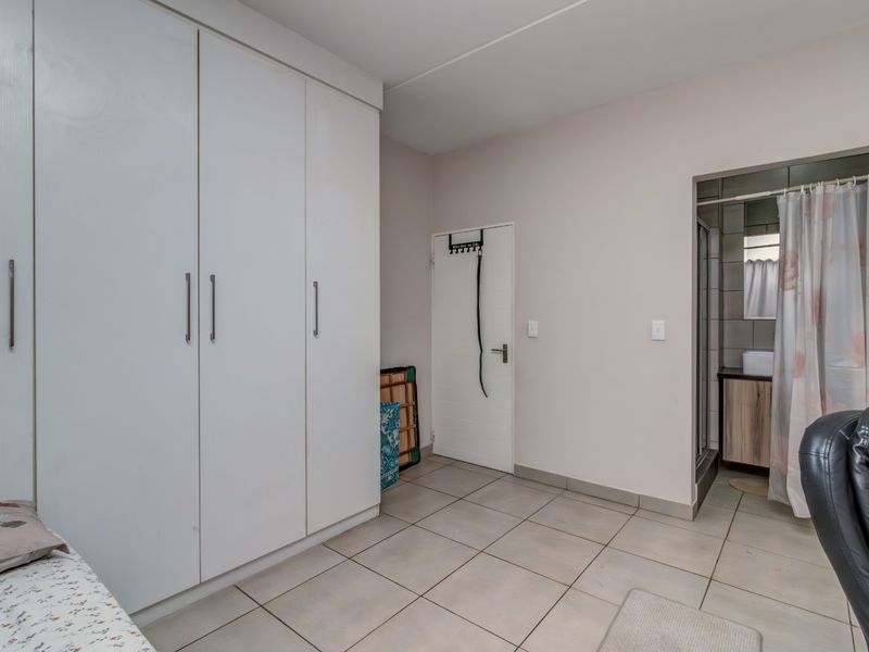 Bedroom featuring built-in cupboards, tiled flooring, and direct access to an en-suite bathroom.