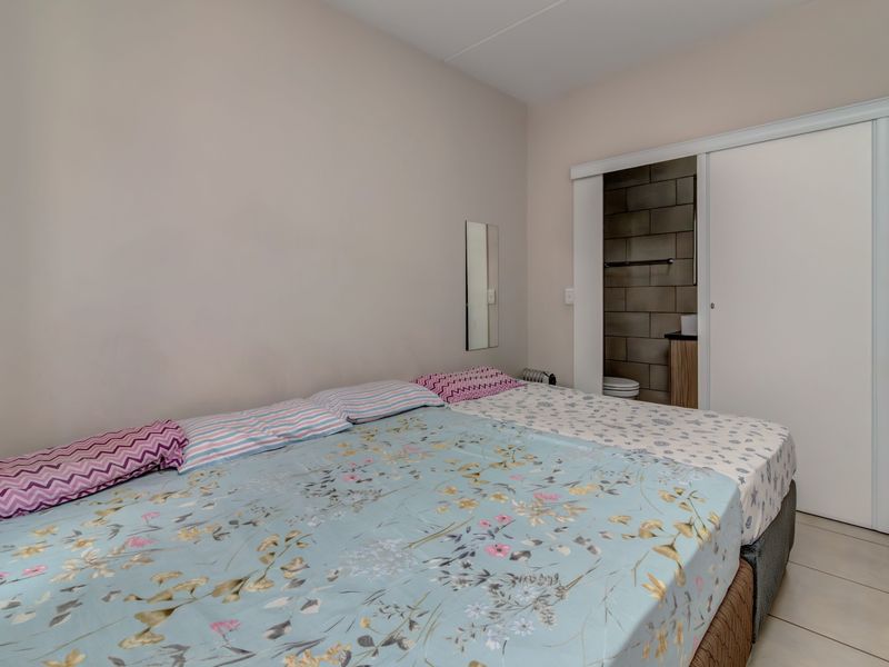 A bedroom featuring tiled flooring and a sliding door providing access to an en-suite bathroom.