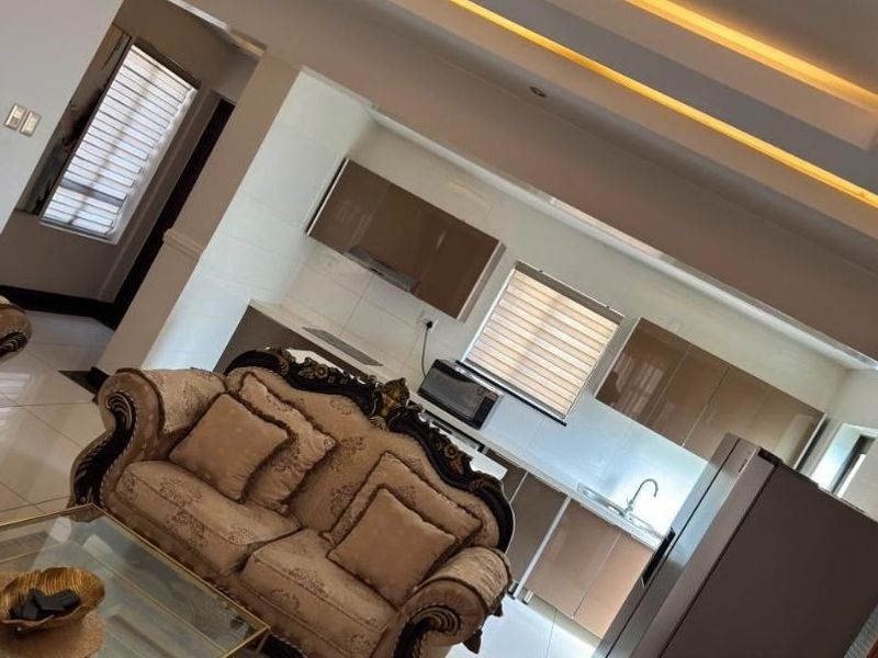 An open-plan living and kitchen area featuring modern recessed ceiling lighting, neutral cabinetry, and tiled flooring throughout.