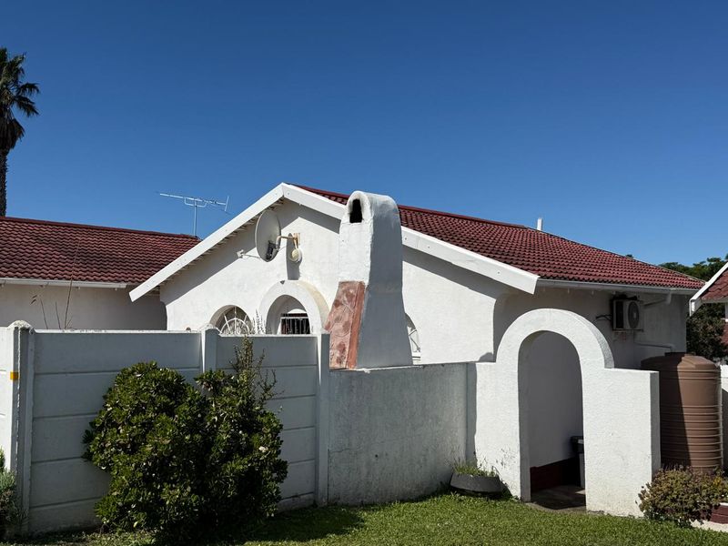 Rear exterior view of the townhouse featuring a tiled roof, external chimney, arched gate, and a water storage tank.