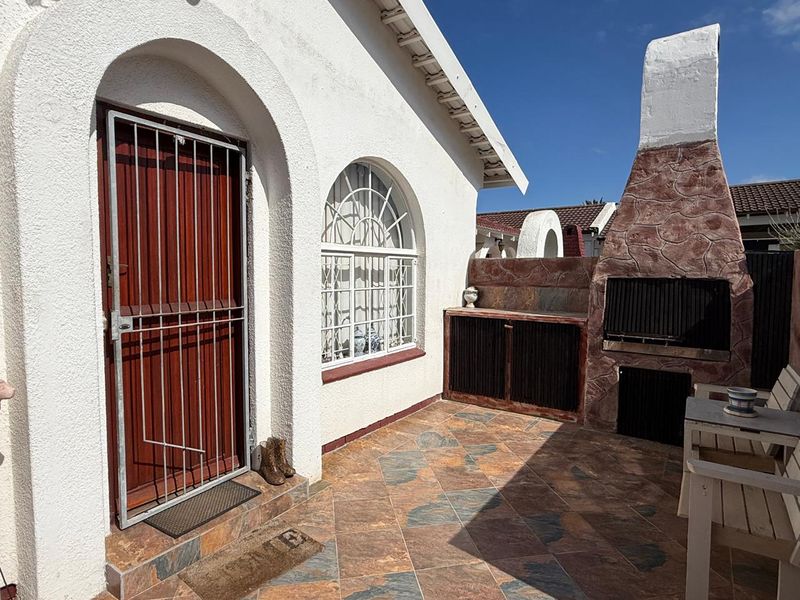Outdoor patio area featuring a built-in braai, tiled flooring, and direct access to the home through a secure entrance.