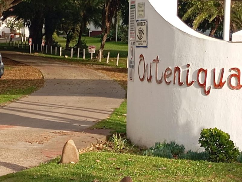 Entrance view of the Outeniqua estate featuring a paved driveway and landscaped surroundings.