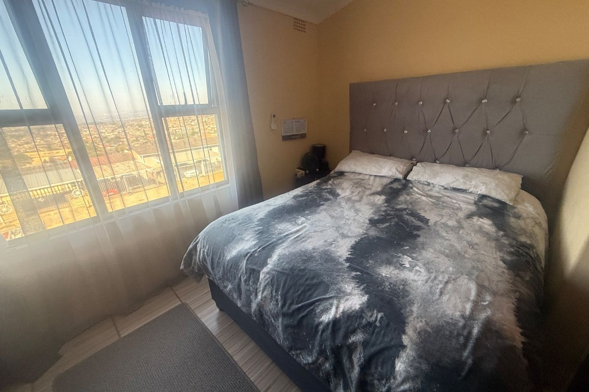 A bedroom featuring laminate flooring and a large window with natural light and views.