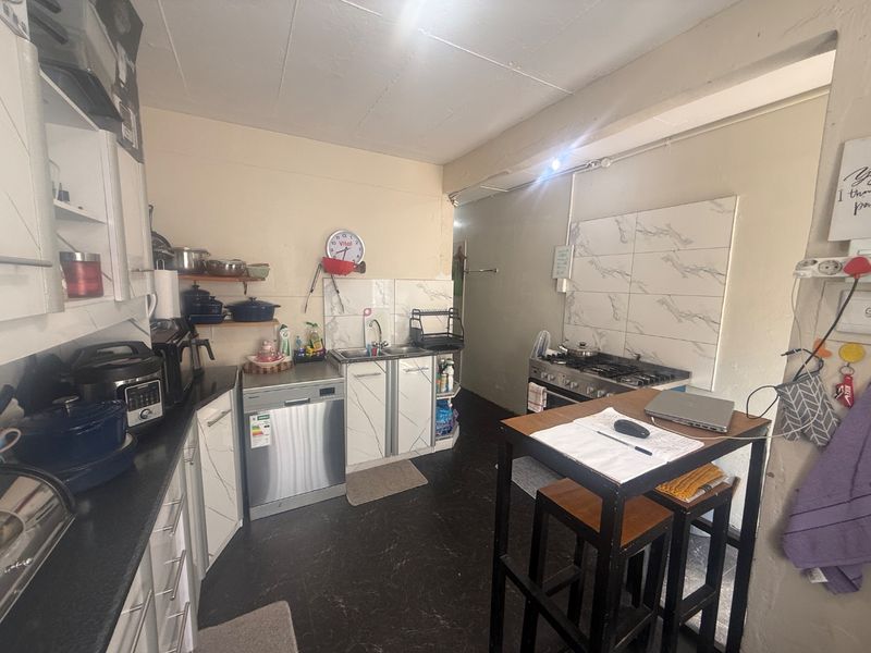 Functional kitchen featuring built-in cabinetry, gas hob, and tiled splashbacks, offering a practical layout with potential for cosmetic updates.
