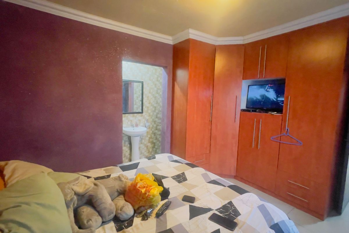 Bedroom featuring built-in wooden cupboards and an open-plan en-suite basin area with decorative wall finishes.
