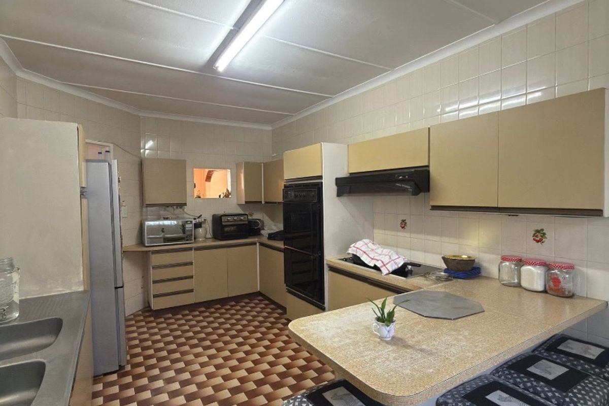 A functional kitchen featuring built-in cabinetry, laminate countertops, a double sink, and integrated oven, offering significant potential for a modern renovation.