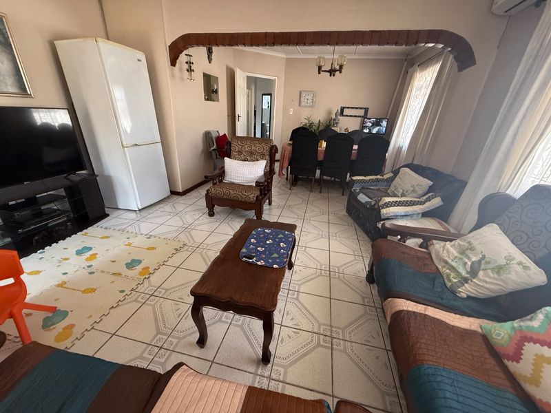 Open-plan living and dining area featuring ceramic floor tiles and a decorative timber archway, providing a functional and connected living space.