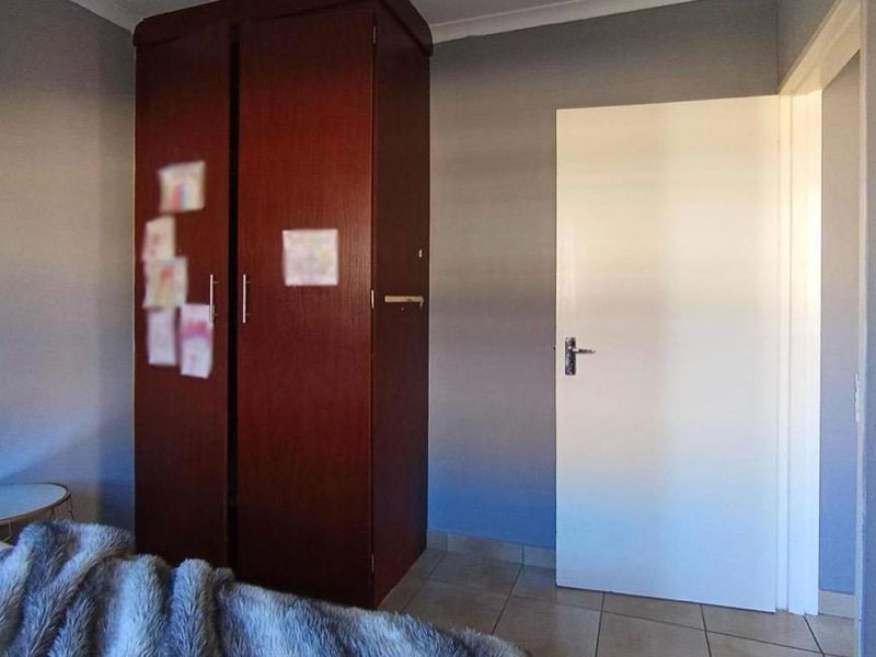 A bedroom featuring tiled flooring and a built-in wooden wardrobe.