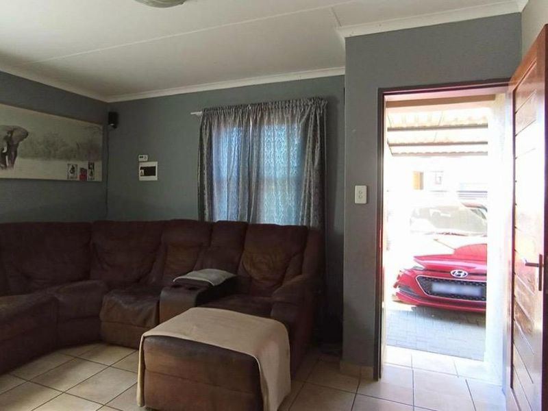 A living room area featuring tiled flooring and direct access to an exterior parking space through a timber door.