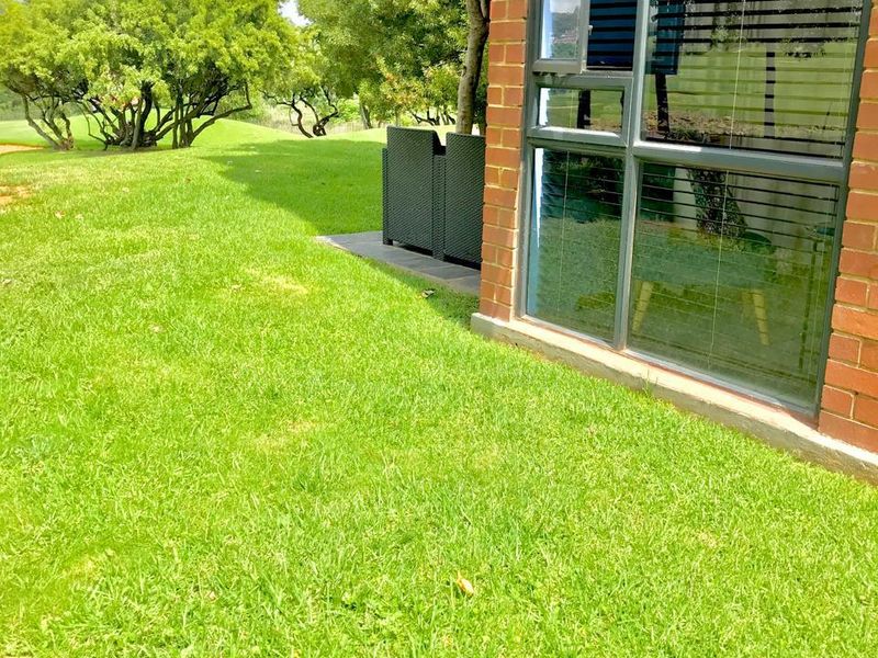 A view of the rear exterior featuring a brick facade, large windows, and a well-maintained lawn area.