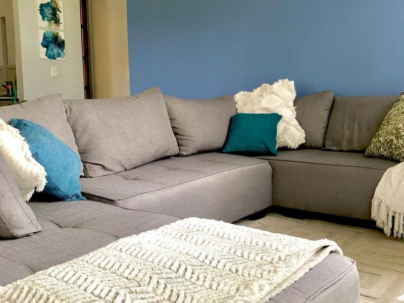 A comfortable living room area featuring tiled flooring and a prominent blue accent wall with crown molding details.