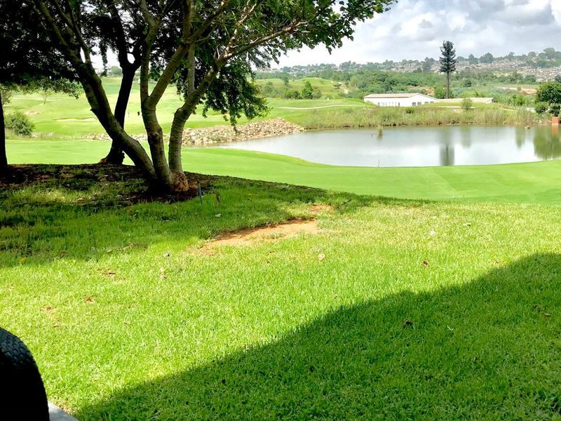A scenic view overlooking a manicured lawn, a tranquil pond, and lush green landscape, providing a peaceful outdoor outlook.