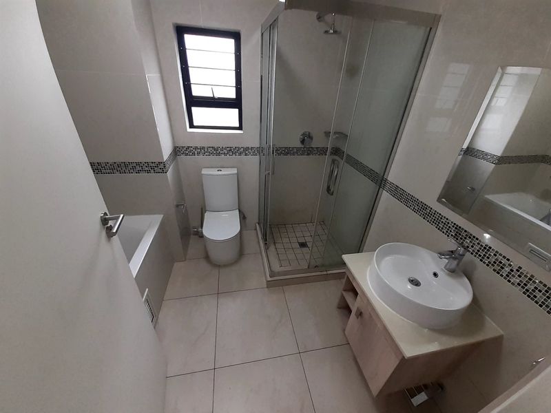 A modern, well-maintained bathroom featuring a separate shower enclosure, bathtub, vanity with vessel sink, and neutral wall and floor tiling.