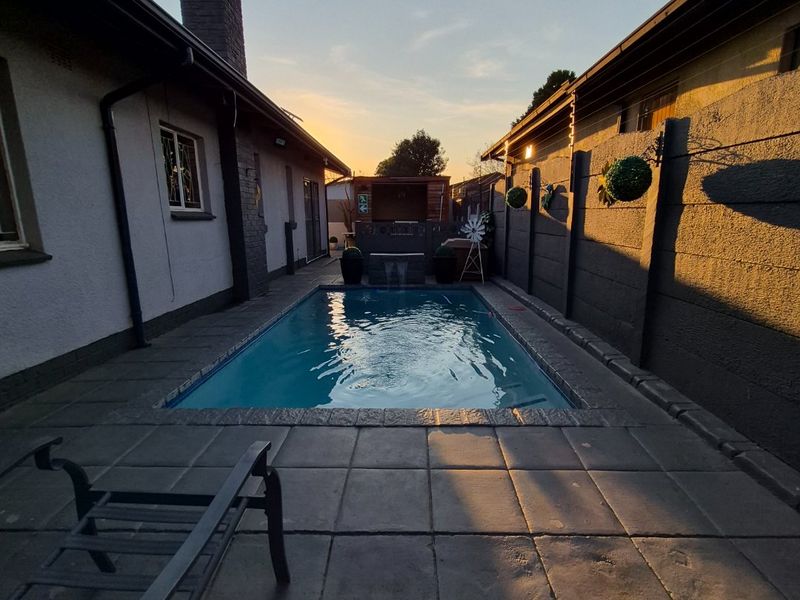 A private outdoor pool area featuring a paved patio, enclosed by boundary walls and the side elevations of the house.