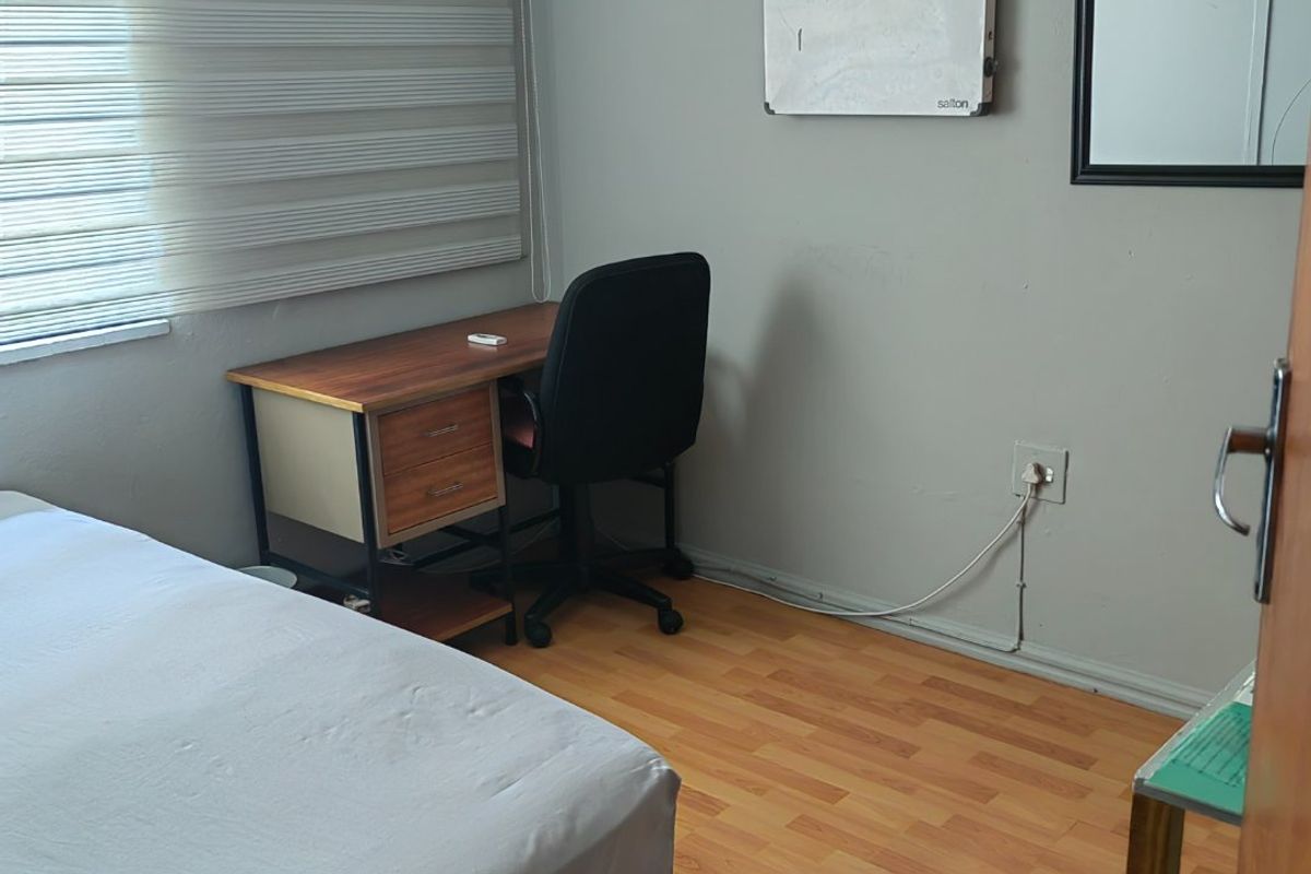 A functional bedroom featuring laminate flooring and roller blinds, providing a neutral space ready for personalization.