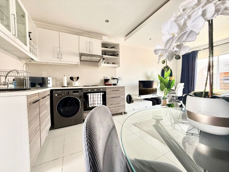 Modern open-plan living area featuring a well-appointed kitchen with built-in cabinetry, integrated oven, and tiled flooring, flowing seamlessly into the living space.