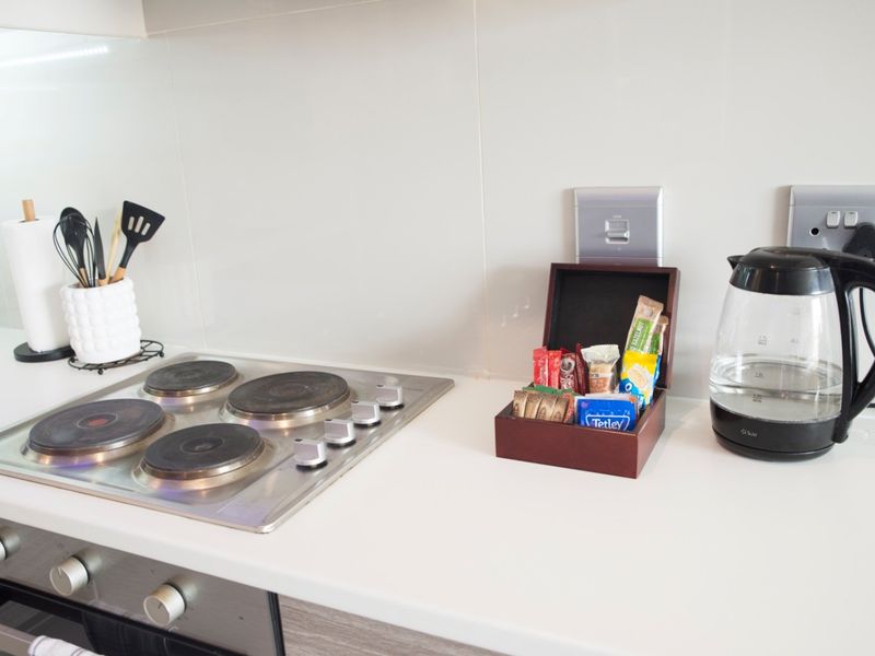 A clean kitchen workspace featuring a modern electric hob, built-in oven, and sleek solid surface countertops with a neutral splashback.