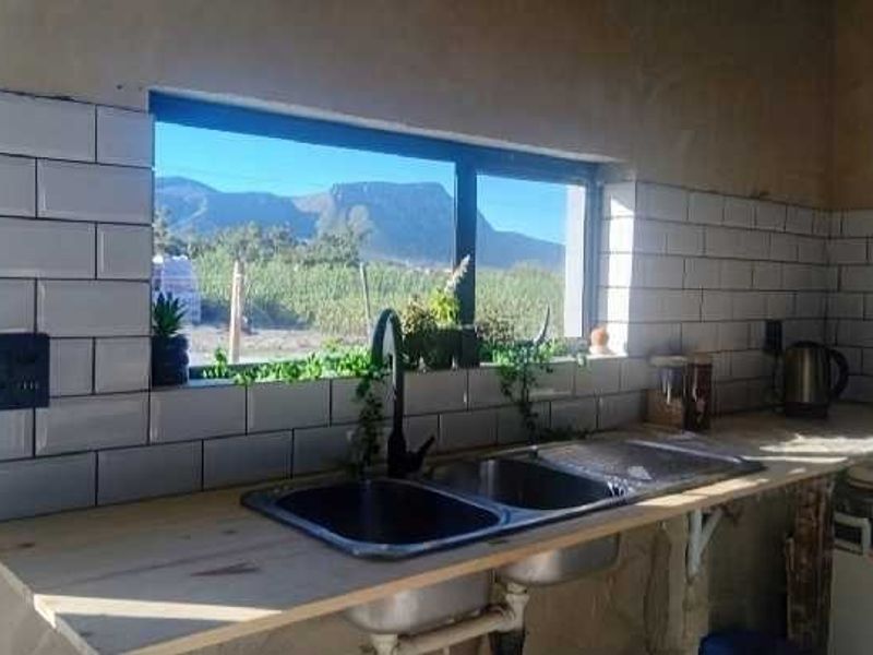 A kitchen area featuring a double bowl sink, wooden countertop, and white subway tile backsplash, with unfinished wall surfaces and scenic mountain views.