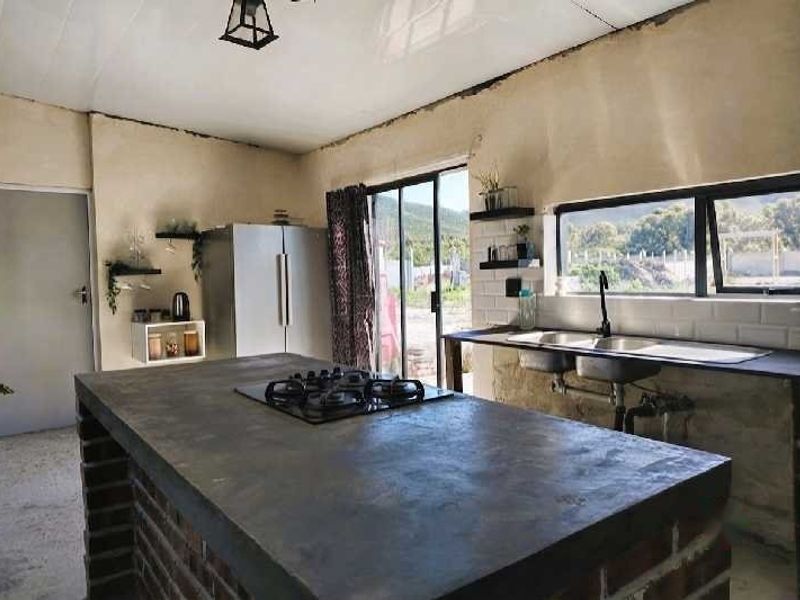 Kitchen featuring a brick island with a gas cooktop, double basin sink, and sliding door access to the exterior. Requires finishing of wall surfaces.