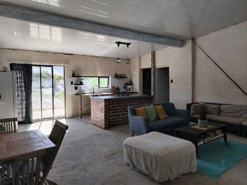 Open plan living and kitchen area featuring an exposed brick island, sliding door access to the exterior, and unfinished interior wall and floor finishes.