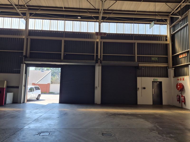 Spacious industrial warehouse unit featuring high ceilings, concrete flooring, and dual roller shutter doors for efficient access.