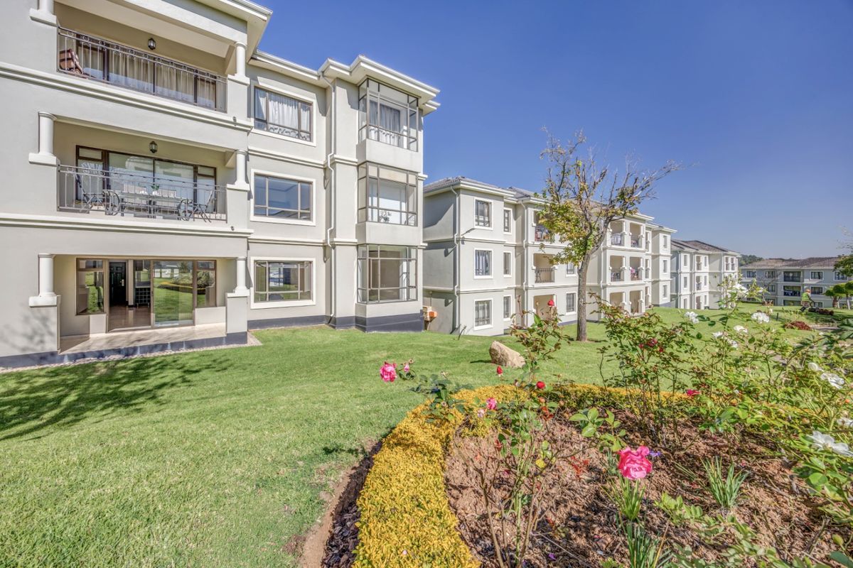 Rear view of the apartment complex featuring multi-level balconies, sliding glass doors, and well-maintained communal garden spaces.