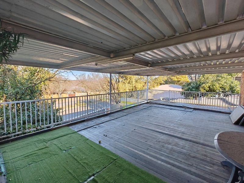 Spacious elevated balcony featuring a corrugated metal roof and timber decking, offering an open outdoor area with metal safety railings.