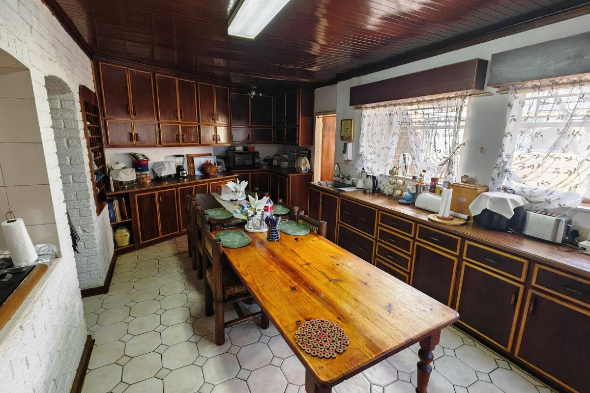 A spacious, dated kitchen featuring extensive wooden cabinetry, timber ceilings, and tiled flooring, offering significant potential for a modern renovation.
