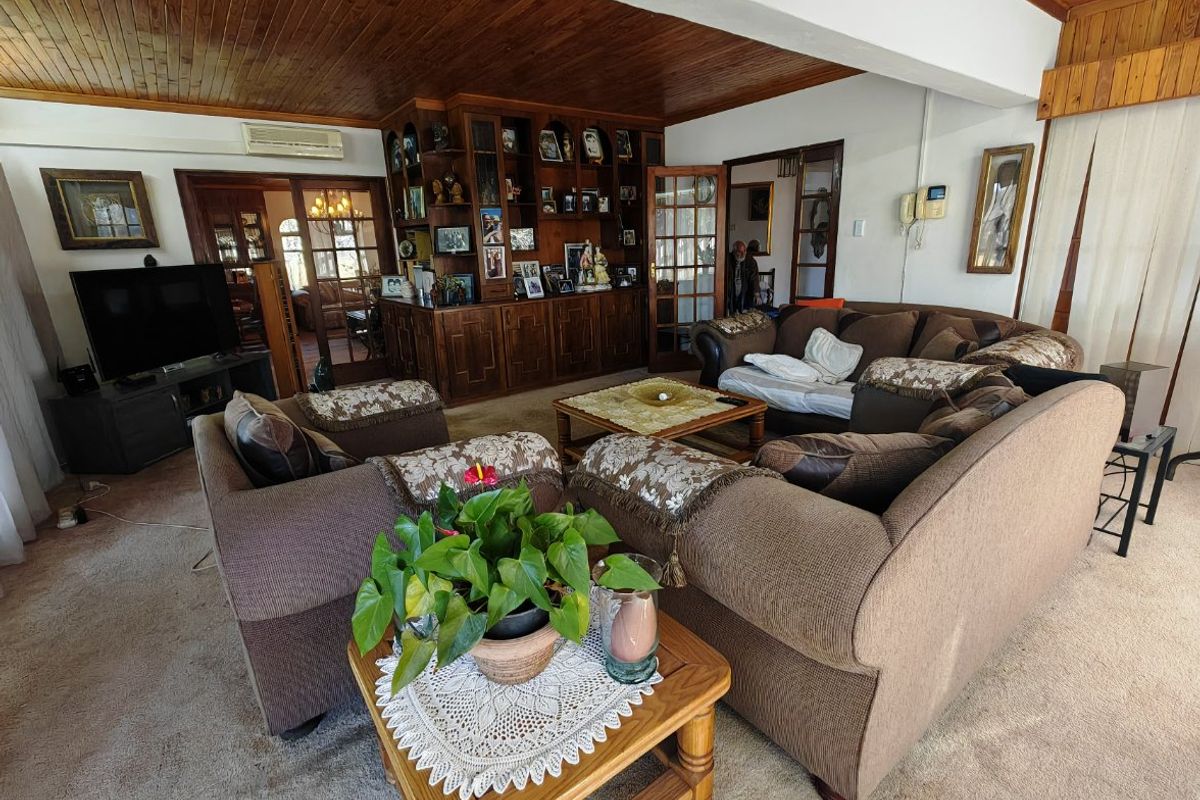 Spacious living room featuring a timber-paneled ceiling, built-in wooden cabinetry, and split-system air conditioning, offering a traditional and cozy atmosphere.