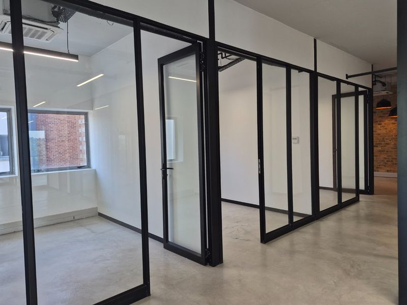 Modern commercial office space featuring polished concrete floors, black-framed glass partitioning, and exposed ceiling services, offering a clean and professional industrial aesthetic.